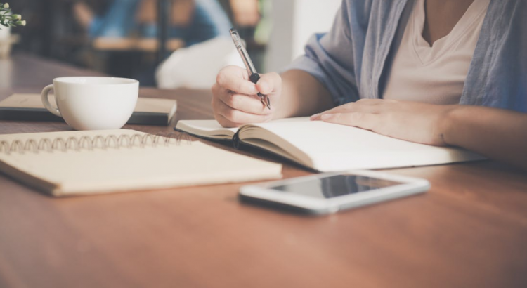 writing in journal with phone in table